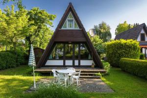 een klein huis met een tafel en stoelen in de tuin bij Ferienwohnpark Immenstaad am Bodensee Nurdachhaus Typ 7 ND 33 in Immenstaad am Bodensee