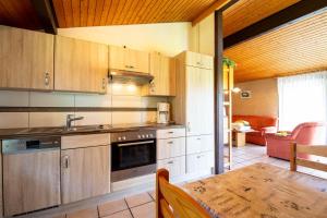 eine Küche mit Holzschränken, einem Tisch und einem Esszimmer in der Unterkunft Ferienwohnpark Immenstaad am Bodensee Satteldachhaus Typ 10 SDS 048 in Immenstaad am Bodensee