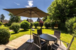 ein Tisch und Stühle mit einem Sonnenschirm auf einer Terrasse in der Unterkunft Ferienwohnpark Immenstaad am Bodensee Nurdachhaus Typ 7 ND 40 in Immenstaad am Bodensee