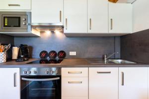una cucina con mobili bianchi e un forno a piano cottura di Ferienwohnpark Immenstaad am Bodensee Satteldachhaus Typ 9 SD 21 a Immenstaad am Bodensee Altre 10 foto