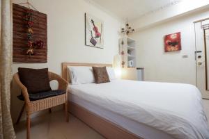 a bedroom with a white bed and a chair at RaRa Stay in Taichung