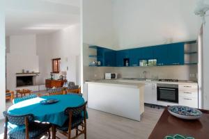 a kitchen with blue cabinets and a table and chairs at Costa Rei, villa Turquesa a 100 m dalla spiaggia in Costa Rei