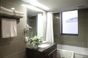 a bathroom with a sink and a vase of flowers at Aventree Hotel Busan in Busan