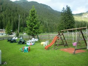 a playground with a slide and chairs in the grass at B&B Agriturismo Cèsa Ciasates in Canazei