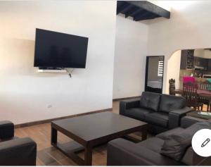 sala de estar con sofá y TV en la pared en Flor de Cera en Valle de Guadalupe