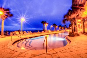 - une piscine avec des palmiers et l'océan la nuit dans l'établissement Calypso 2-2007 ! Amazing Location, And Awesome OCEAN Views!, à Panama City Beach