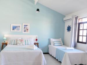 two beds in a room with blue walls at Viva Buzios in Búzios
