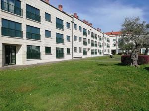 a large white building with a grass field in front of it at PISO COLLAZO in Isla de Arosa