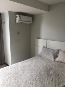 1 dormitorio con 1 cama blanca y aire acondicionado en Atlântico Flat Apt 210 en Natal