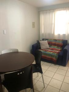 een woonkamer met een bank en een tafel en stoelen bij Atlântico Flat Apt 210 in Natal