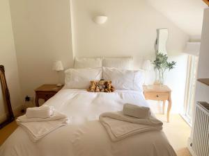 a white bed with two teddy bears sitting on it at Luxury barn conversion near Salcombe & Kingsbridge, South Devon in Kingsbridge