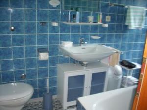 a blue tiled bathroom with a sink and a toilet at Gästehaus Stoanerhof in Unterwössen
