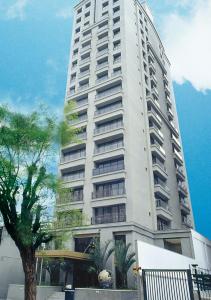 a tall white building with a tree in front of it at Estanplaza Paulista in Sao Paulo