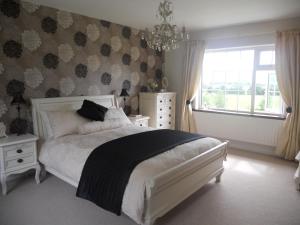 1 dormitorio con cama, ventana y lámpara de araña en Broomfields en Greenane