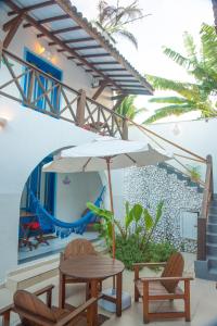 une terrasse avec une table, des chaises et un parasol dans l'établissement Vila Mucugê Pousada e Hostel, à Arraial d'Ajuda