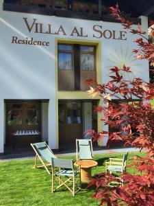 three chairs and a table in front of a building at Residence Villa al Sole in Selva di Val Gardena