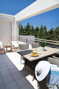 eine Terrasse mit einem Tisch und Stühlen auf dem Balkon in der Unterkunft LOTOS - Luxury Apartments in Kounoupidiana