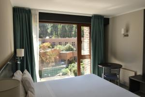 a bedroom with a bed and a large window at Hotel Bosque de Reñaca in Viña del Mar