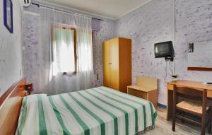 una camera con letto, scrivania e TV di Hotel Antonella a Caorle