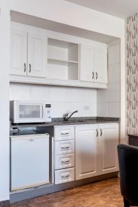 a kitchen with white cabinets and white appliances at Ker Belgrano Hotel in Buenos Aires