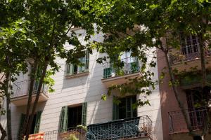 バルセロナにあるCentric Apartments Sagrada Famila 3の緑の窓と木々が植えられた白い建物