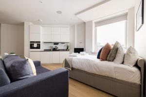 a bedroom with a bed and a couch and a kitchen at The Kingston Upon Thames Studios in Surbiton