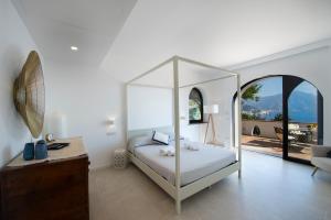 a bedroom with a white canopy bed with a view at APPARTAMENTO LE MIRAGE in Conca dei Marini