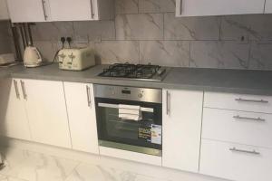 KentにあるThe Dartford Five Bedrooms Attractive Houseのキッチン(コンロ、白いキャビネット付)