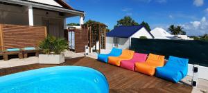 un sofá colorido sentado en una terraza junto a una piscina en Tropical Dream - Gîte Touristique - 4Adultes et 3Enfants, en Baie-Mahault
