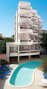 - un grand bâtiment blanc avec une piscine en face dans l'établissement Hotel Prestige, à Cattolica