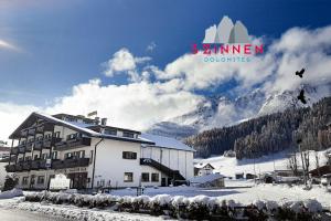 un edificio en la nieve junto a una montaña en Hotel Comelico, en Padola