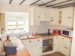a kitchen with white cabinets and a sink at Heathylee in Longnor