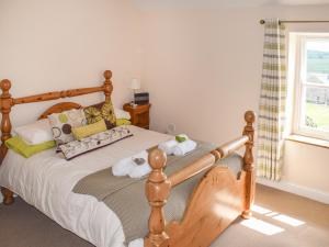 a bedroom with a wooden bed and a window at Heathylee in Longnor
