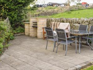 a patio with a table and chairs and a stone wall at Heathylee in Longnor