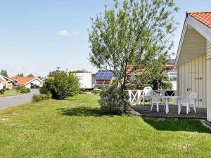 um pátio com cadeiras brancas e uma mesa num quintal em 4 person holiday home in Otterndorf em Otterndorf