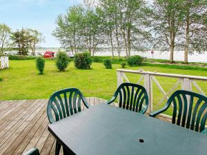 a table and chairs on a deck with a view of the ocean at 8 person holiday home in Gelting in Gelting