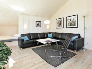 ein Wohnzimmer mit einem schwarzen Sofa und einem Tisch in der Unterkunft 8 person holiday home in Gro enbrode in Großenbrode