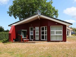 a red shed with a chair in a field at 6 person holiday home in GROEMITZ in Grömitz