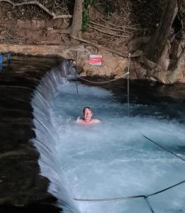a man swimming in a waterfall in a swimming pool at Rio Quente Aguas da Serra Apart in Rio Quente