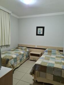 um quarto com 2 camas, uma mesa e um espelho em Rio Quente Aguas da Serra Apart em Rio Quente