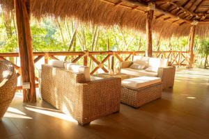 een patio met rieten stoelen en een bank op een veranda bij Refugio Monte Oscuro in Las Mercedes