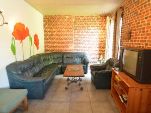 un soggiorno con divano in pelle e TV di Spacious house in a farm located in the bucolic a Teuven