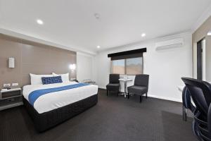 a hotel room with a bed and a table and chairs at Bluegum Dubbo in Dubbo +7 photos