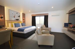 a hotel room with a bed and a chair at Bluegum Dubbo Motel in Dubbo