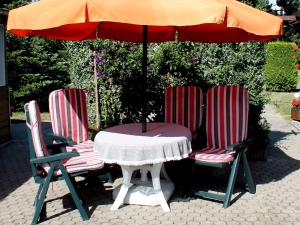2 Stühle und ein Tisch mit Sonnenschirm in der Unterkunft Pretty Bungalow in Neubukow with Garden, Roof Terrace, BBQ in Neubukow