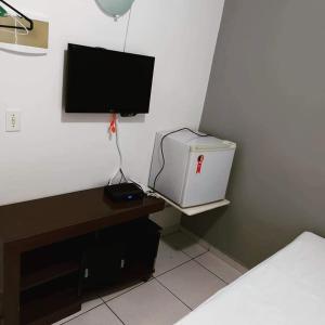 een slaapkamer met een televisie en een bureau met een computer bij Pousada Surya in Porto Velho