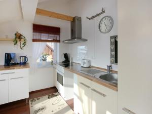 una cocina con armarios blancos y un reloj en la pared en Apartment in Dietmannsried near the forest, en Dietmannsried