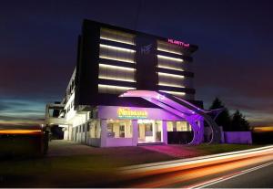 Un edificio iluminado con un restaurante enfrente. en Hilarity Inn, en Padappai