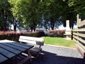 een houten picknicktafel en een bank in een park bij Small simple and reasonably priced semi detached house with its own terrace in Houffalize