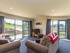 a living room with two couches and sliding glass doors at Kowhai Heights - Ohakune Holiday Home in Ohakune